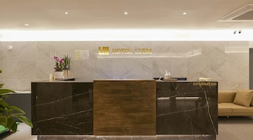 Mostrador de recepción de hotel con encimera de mármol, panel de madera y un letrero que dice 'HOTEL LUEM'.