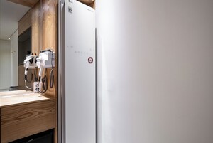 Una cocina moderna con refrigerador empotrado, encimera de madera y cafetera de pared.