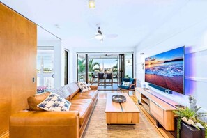 Ein modernes Wohnzimmer mit einer Ledersofa, einem Couchtisch und einem Flachbildfernseher.