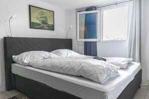 A bed with a quilted white duvet, a dark headboard, and a framed picture on the wall. - Cozy Room With Shared Garden Access (Vienna)