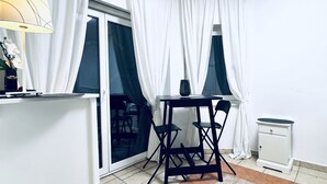 A room with a dining table, chairs, a lamp, a small cabinet, and a radiator. - Cozy Room With Shared Garden Access (Vienna)