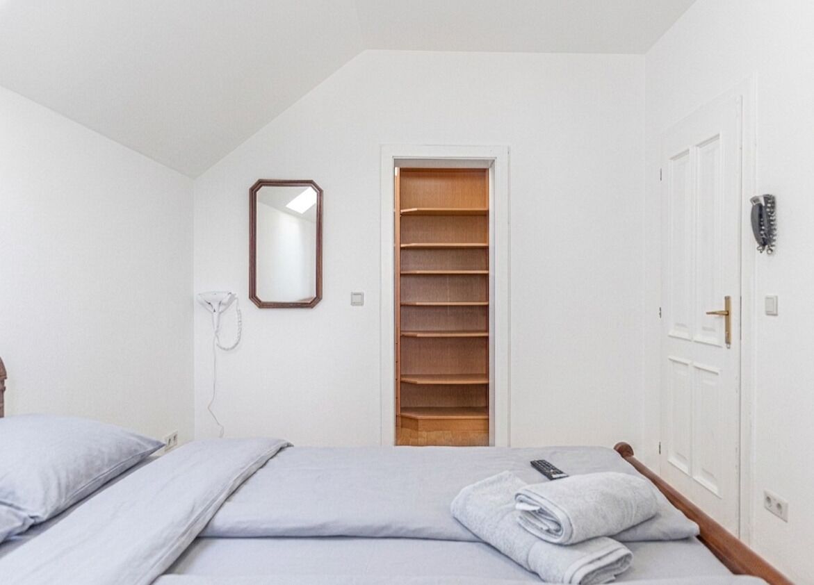 Un dormitorio con cama, espejo, teléfono, puerta y armario.