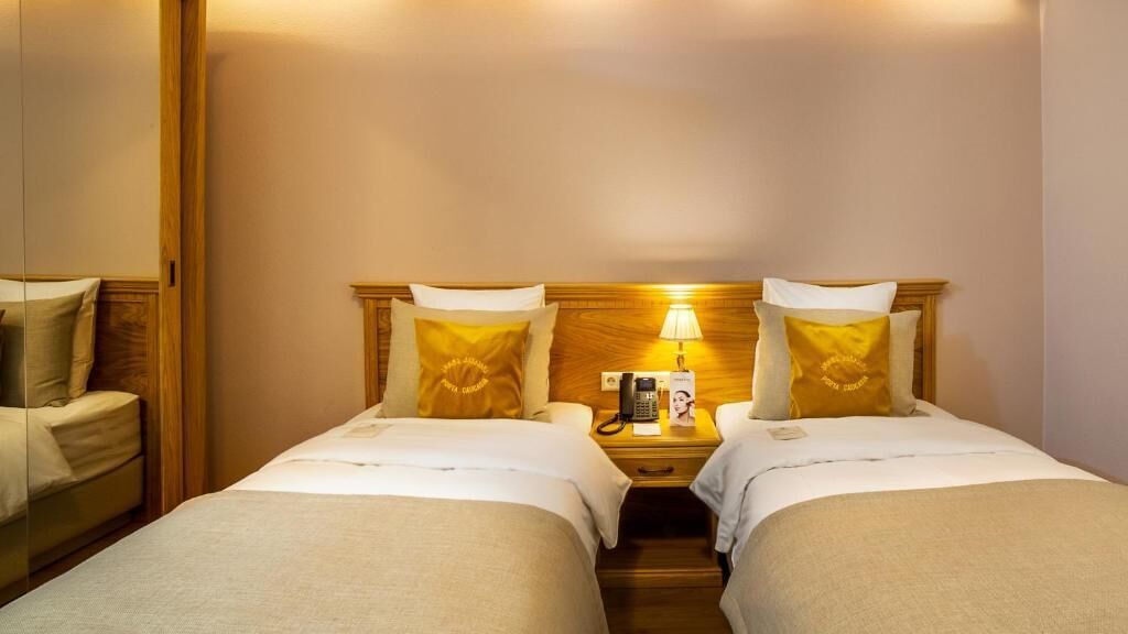 Une chambre double avec deux lits, une tête de lit en bois, des lampes de chevet, un téléphone et une table de chevet.