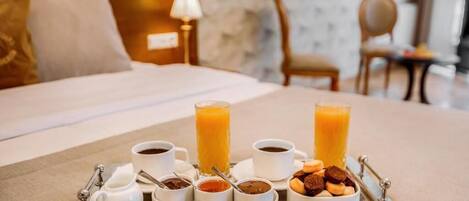 Bandeja de desayuno con café, jugo y pastelería en una habitación de hotel.