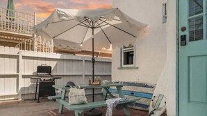 Une terrasse avec un barbecue, une table de pique-nique et un banc.