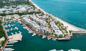 Ein Yachthafen mit anlegenden Booten, ein Strand und Wohnhäuser.