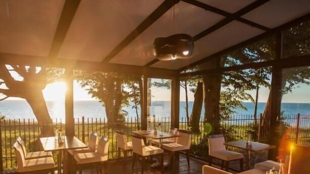 Un espace extérieur aménagé avec des tables et des chaises, une pergola et une vue sur la mer.
