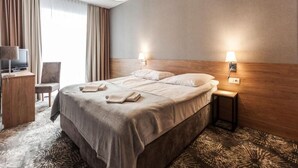 Une chambre d’hôtel avec un lit, deux lampes de chevet, un bureau avec une télévision et une chaise.
