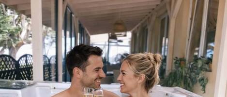 A couple in a hot tub with a covered patio and outdoor seating.