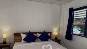 Ett hotellrum med en snyggt bäddad säng, två sänglampor, ett fönster med gardiner och utsikt över omgivningen.