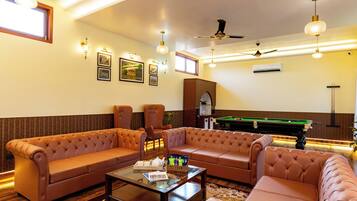 A room with a pool table, two sofas, a coffee table, and wall-mounted lights.