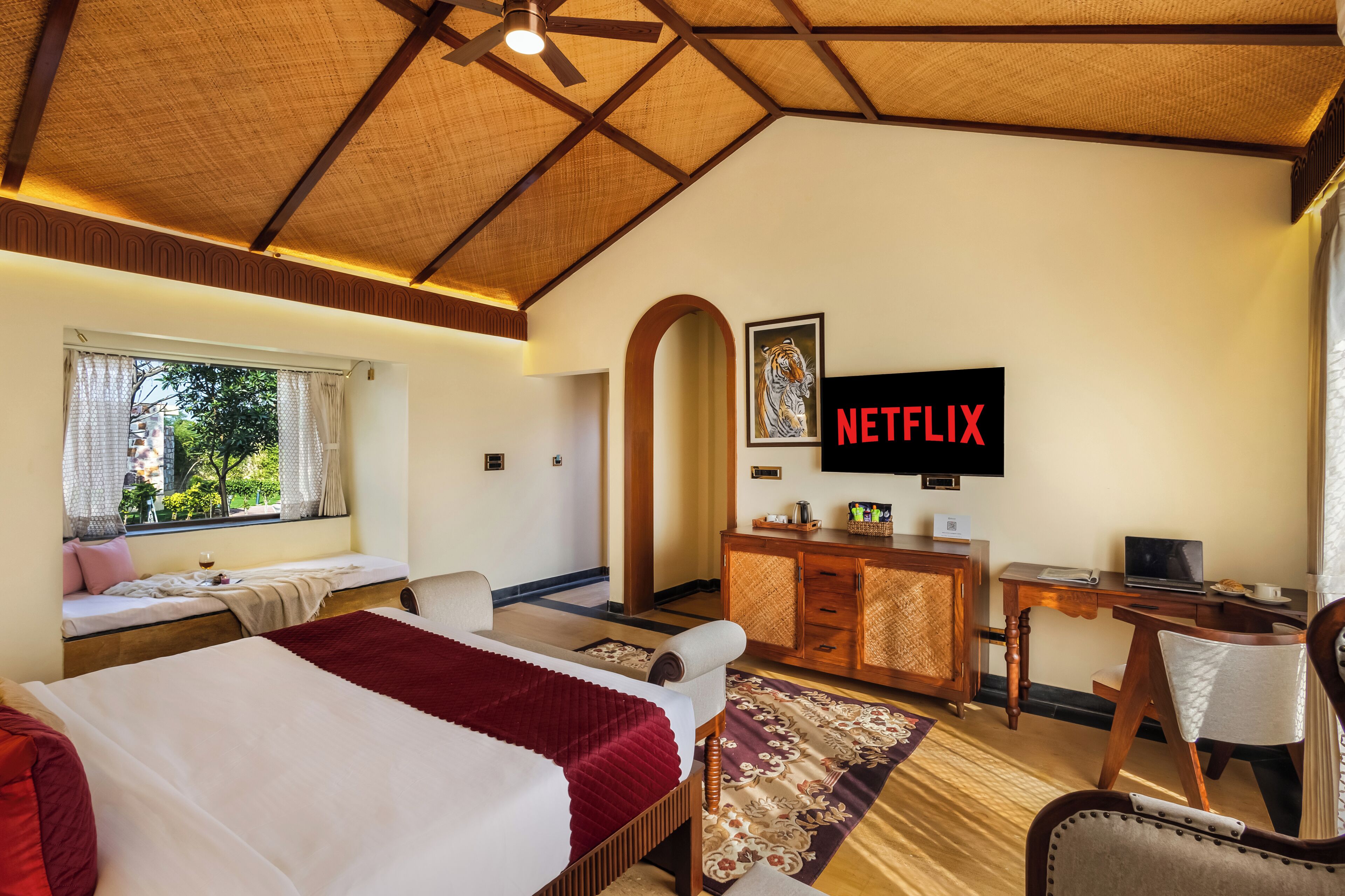 A hotel room with a bed, a desk, a TV, and a window with curtains.