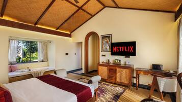 A hotel room with a bed, a desk, a TV, and a window with curtains.