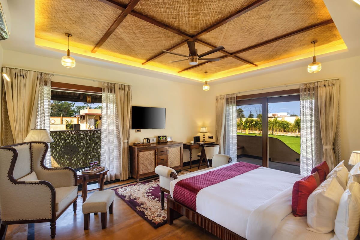 A hotel room with a bed, a desk, a chair, a TV, and a balcony with a view.