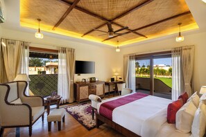 A hotel room with a bed, a desk, a chair, a TV, and a balcony with a view.
