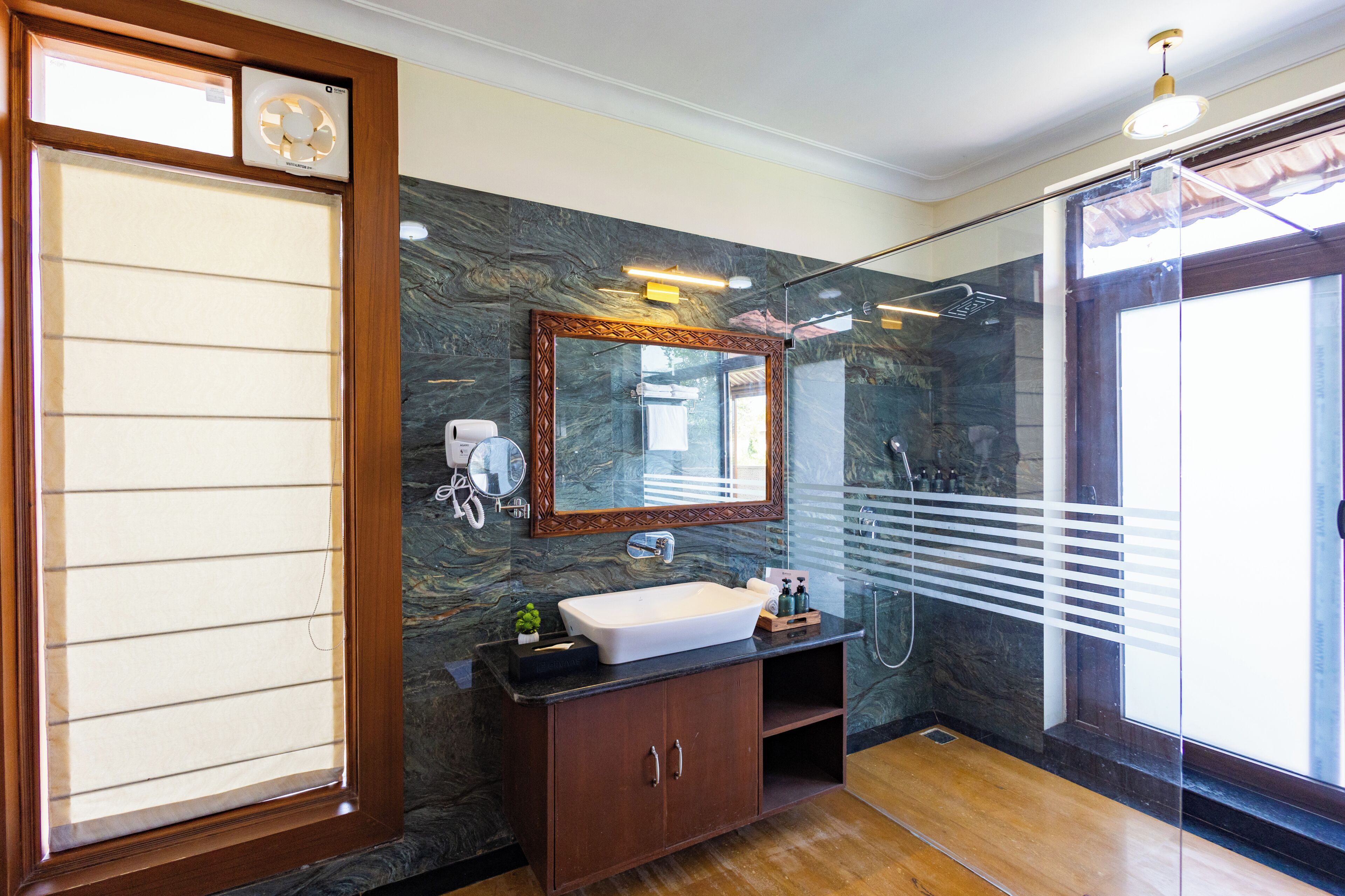 A bathroom with a large mirror, a sink, a shower, and a wooden cabinet.