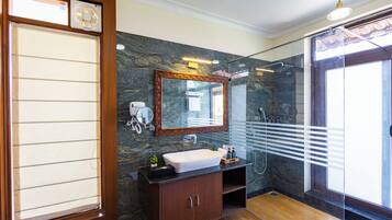 A bathroom with a large mirror, a sink, a shower, and a wooden cabinet.
