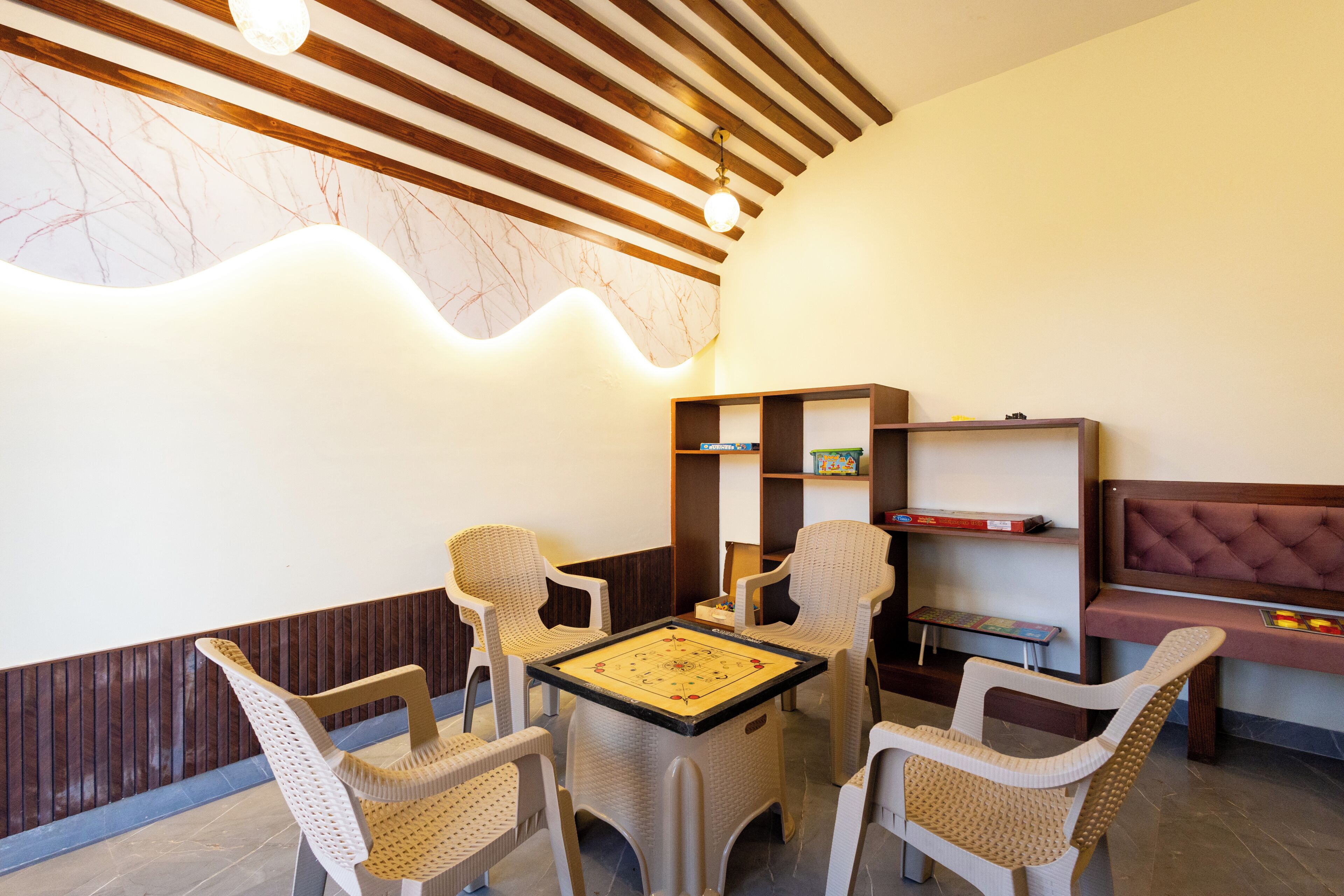 A room with a wooden ceiling, a marble wall, wicker chairs, a small table, and a bookshelf.