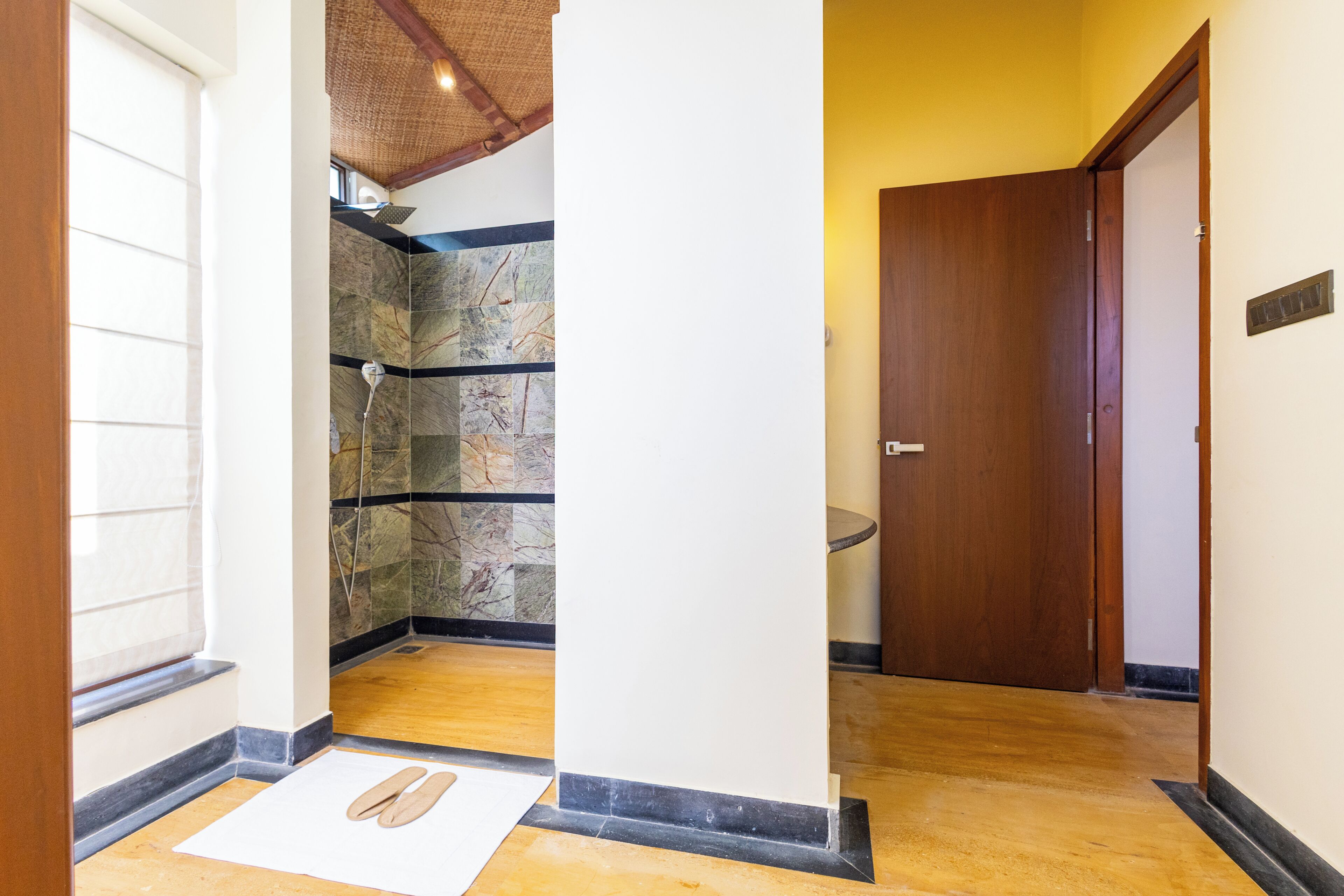 A hallway with a wooden door, a stone wall, and a pair of slippers on the floor.