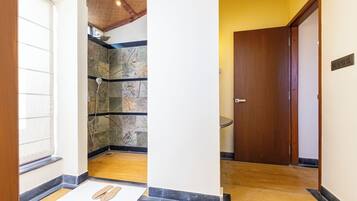 A hallway with a wooden door, a stone wall, and a pair of slippers on the floor.