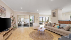 Una sala de estar con televisor, sofá, mesa de centro y puerta corrediza de vidrio que da a un balcón.