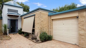 Una propiedad residencial con garaje, un patio cubierto y un muro exterior de piedra.