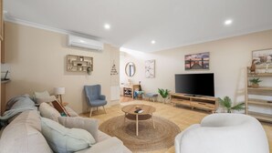 Una sala de estar con sofá, sillón, televisor y una mesa de centro.