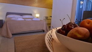 Een hotelkamer met een bed, een nachtkastje met een schaal fruit, en uitzicht op het omliggende landschap.