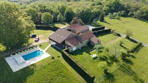 Vue aérienne d’un vaste domaine comprenant plusieurs bâtiments, une piscine et de beaux jardins bien entretenus.