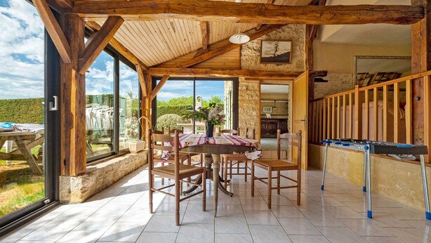 Un coin repas avec une table dressée pour quatre personnes, des chaises en bois et une vue sur l’extérieur.
