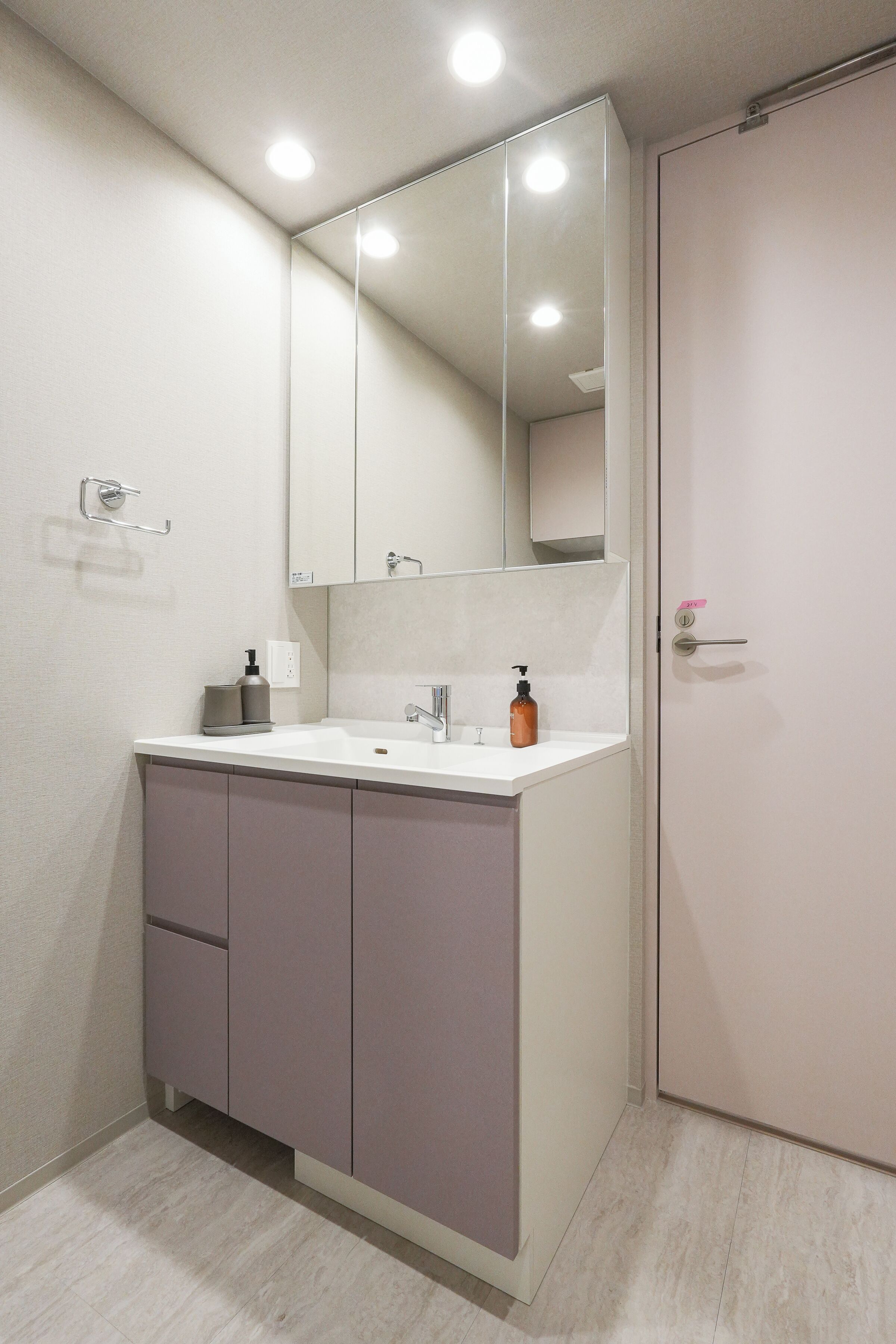 A bathroom with a white sink, a mirror, and a door.