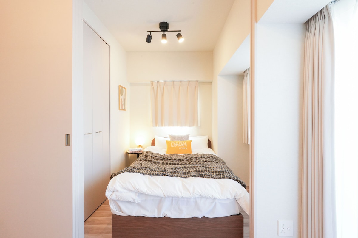 Een slaapkamer met een bed, nachtkastje, lamp en gordijnen.
