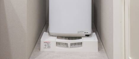 A compact room with a white appliance, possibly a washer, on a stand, a door, and a wall socket.