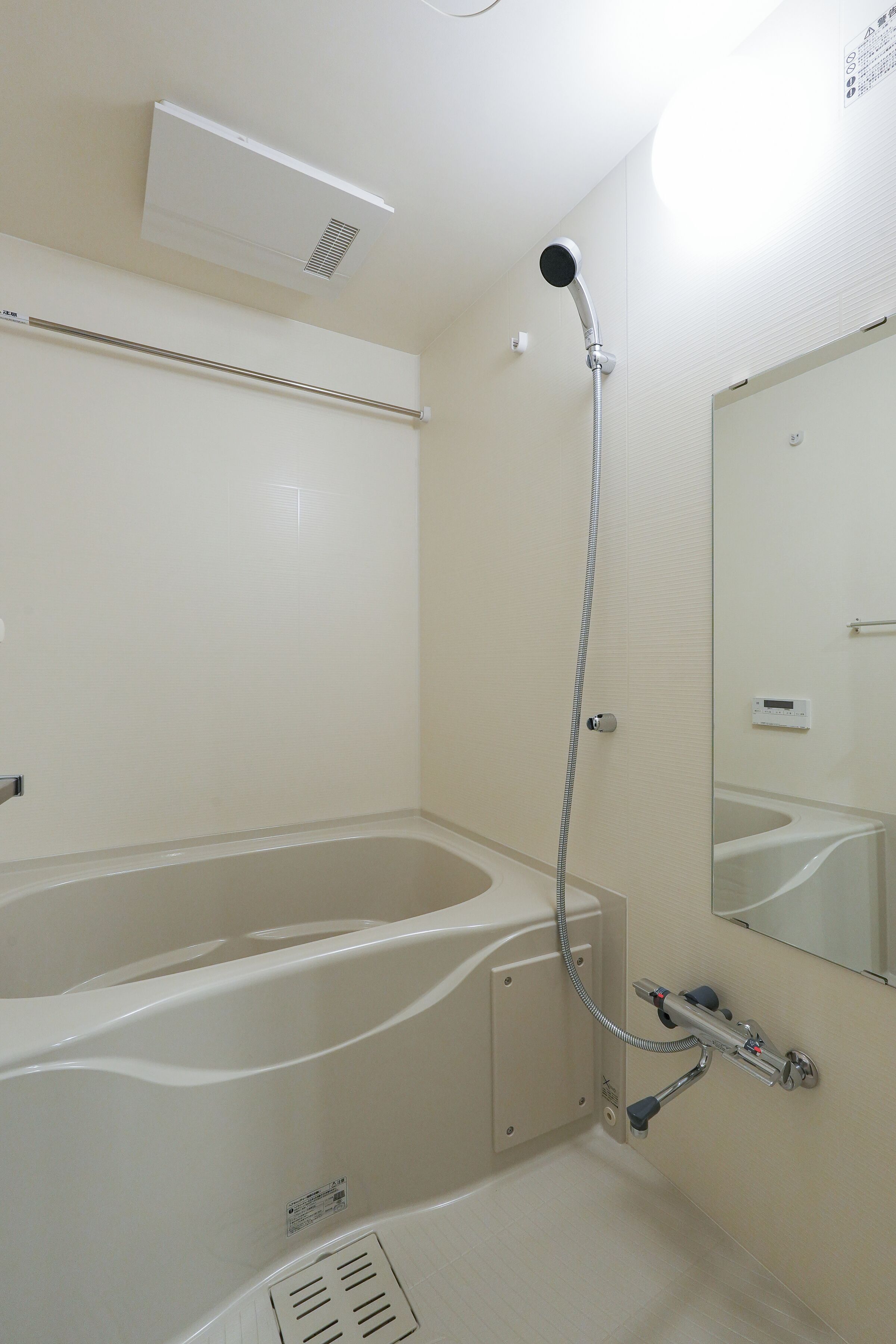 A bathroom with a bathtub, a showerhead, a mirror, and a vent.