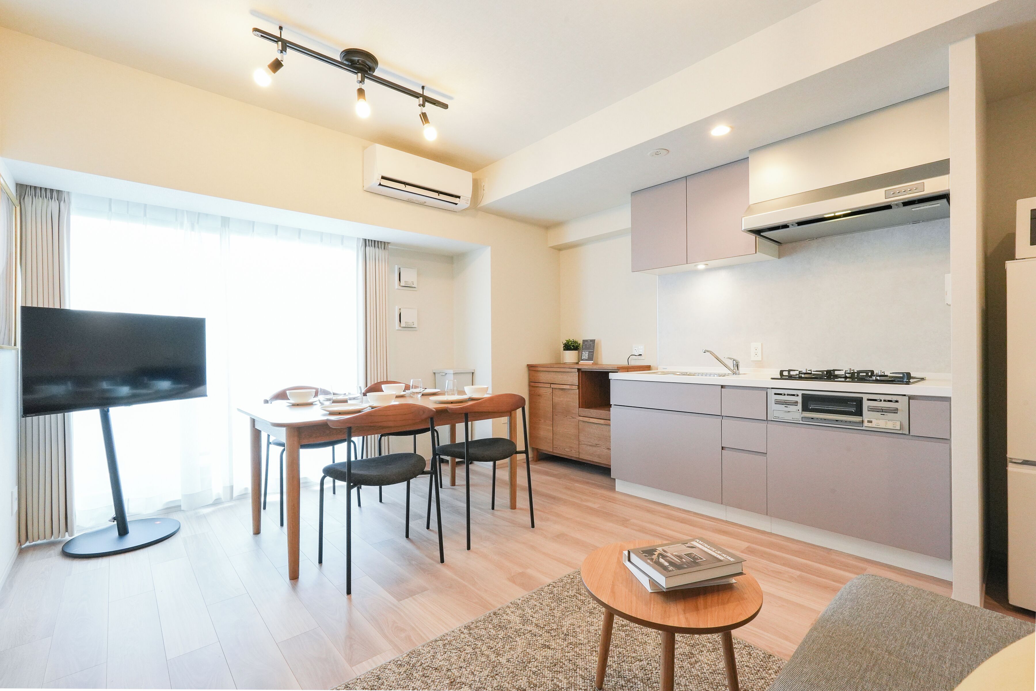 A modern kitchen with a dining area, a flat-screen TV, and a small table with a book.