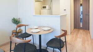 A modern dining area with a round table, four chairs, and a potted plant. - Dash Living Asakusa South (Tokyo)