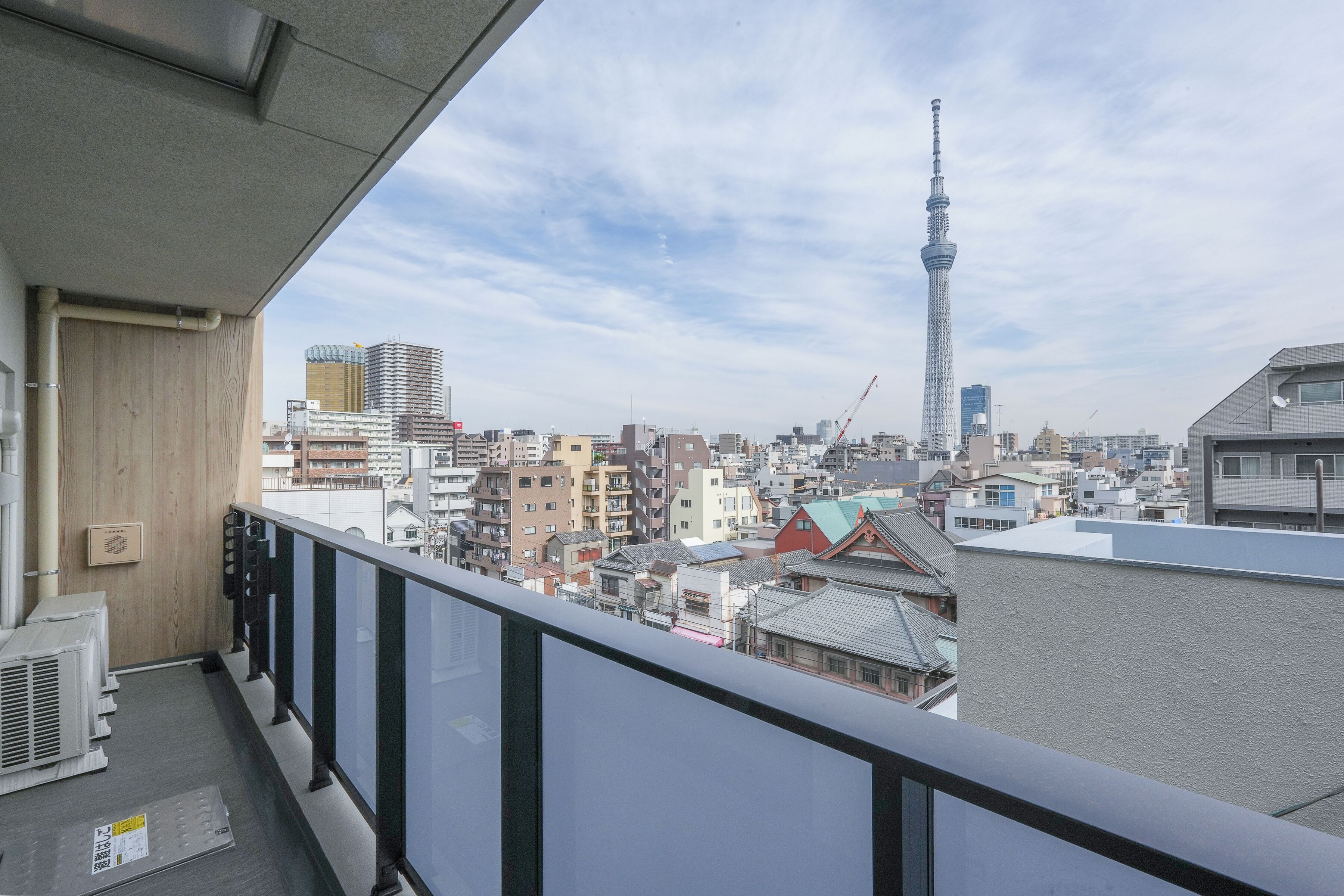 Een stadsgezicht met een opvallende toren, woongebouwen en een balkon met hekwerk.