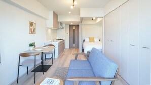 A modern apartment with a kitchenette, a dining area, a sofa, and a wardrobe. - Dash Living Asakusa South (Tokyo)