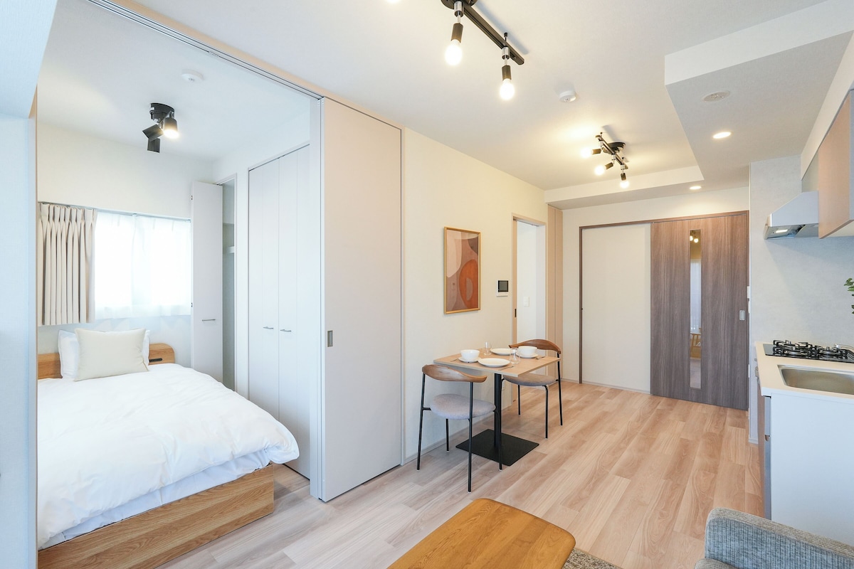 Ett modernt hotellrum med en säng, ett matbord och ett litet kök.