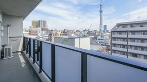 A balcony with a view of a cityscape, including a tower and various buildings. - Dash Living Asakusa South (Tokyo)