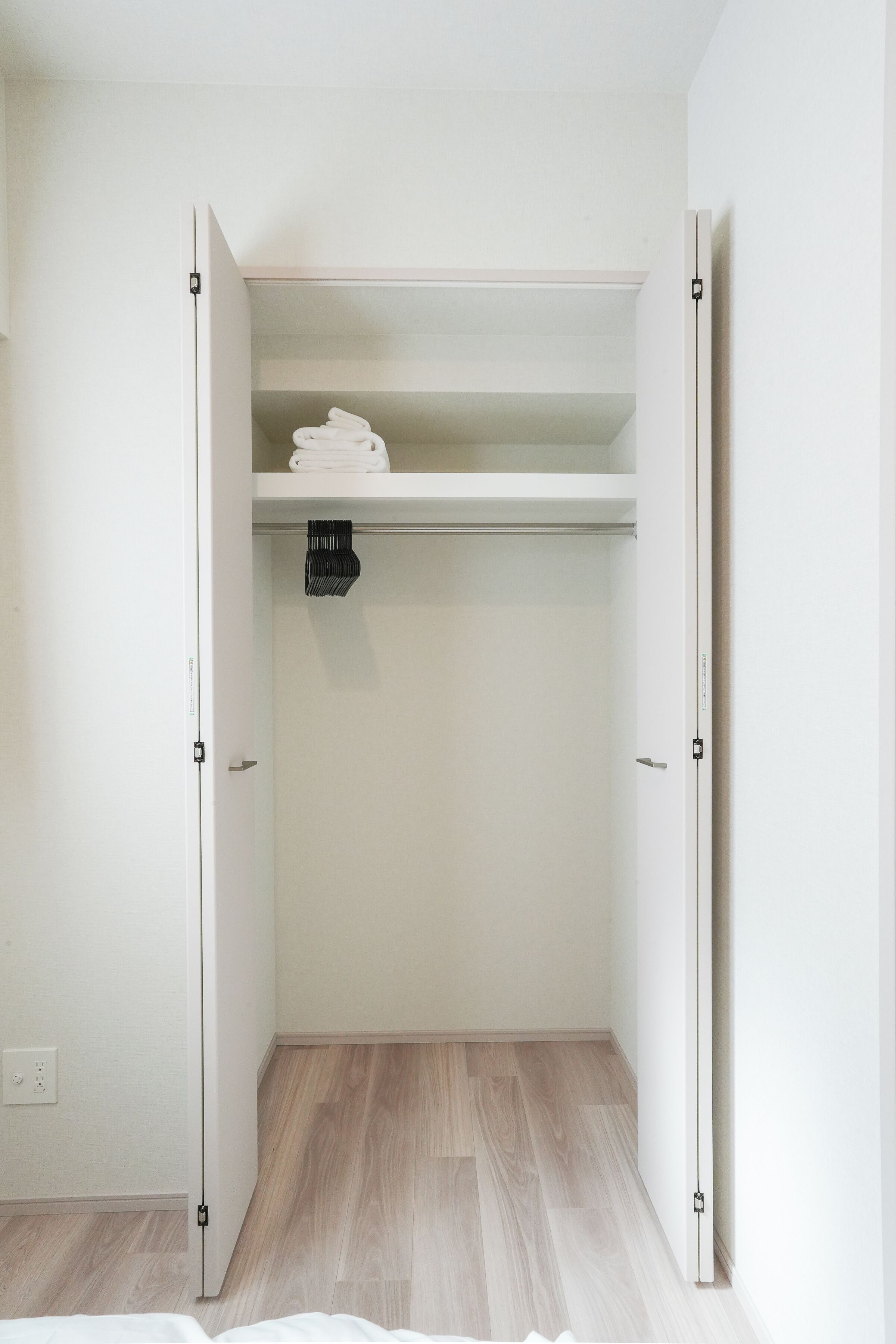 Un closet amplio con piso de madera, una barra para colgar ropa y un estante con toallas dobladas.