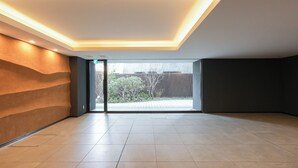 A spacious room with a large sliding glass door leading to an outdoor area, recessed ceiling lighting, and a tiled floor. - Dash Living Asakusa South (Tokyo)