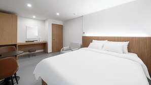 A modern hotel room with a large bed, a desk, a chair, and a wooden panel wall. - Hotel Amigo Pyeongtaek Songtan (Pyeongtaek)