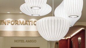 A hotel reception area with a modern chandelier, a reception desk, and a wall with the hotel's name. - Hotel Amigo Pyeongtaek Songtan (Pyeongtaek)