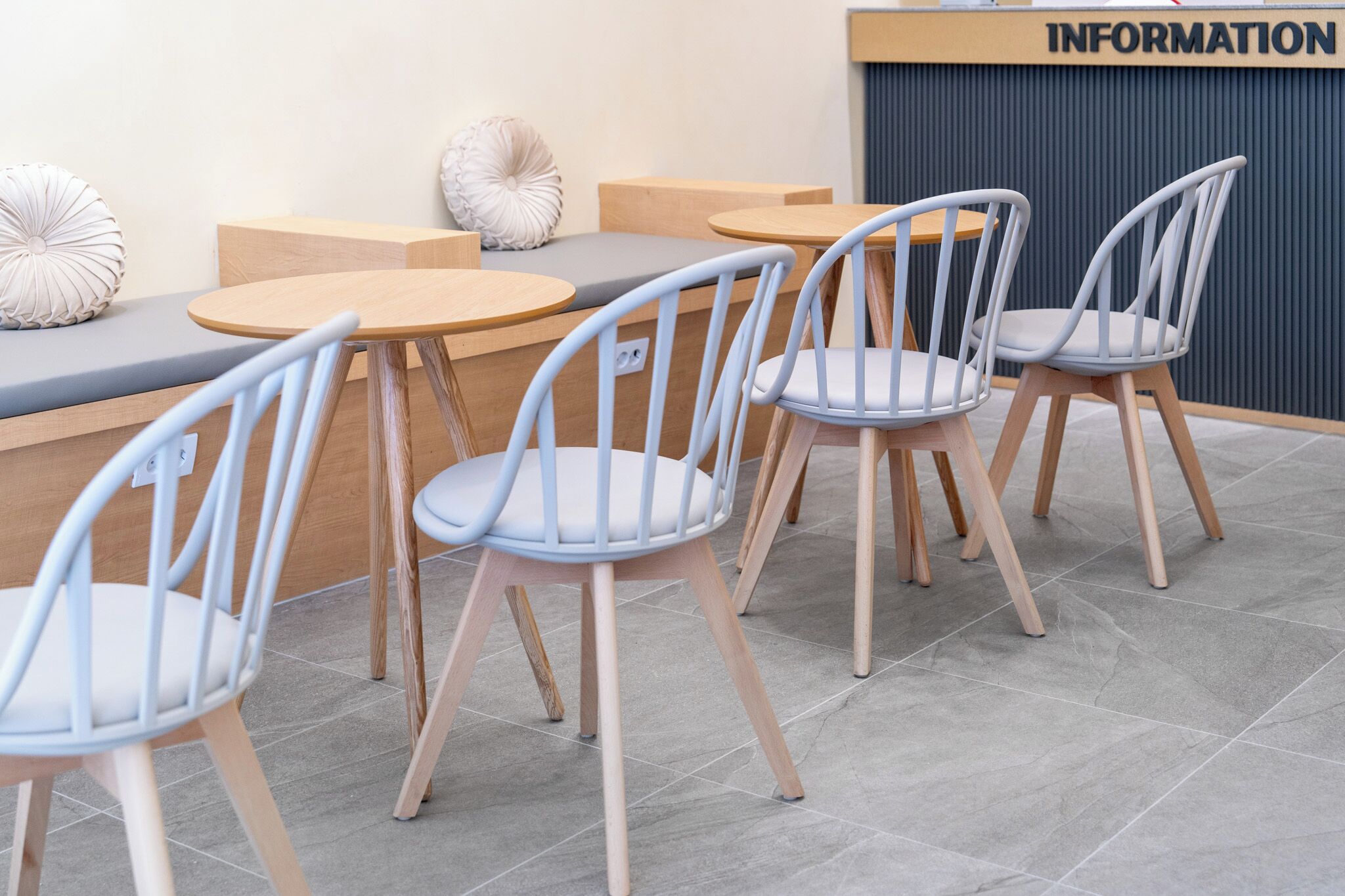 A seating area with round tables and chairs, a bench, and a wall with an 'INFORMATION' sign.