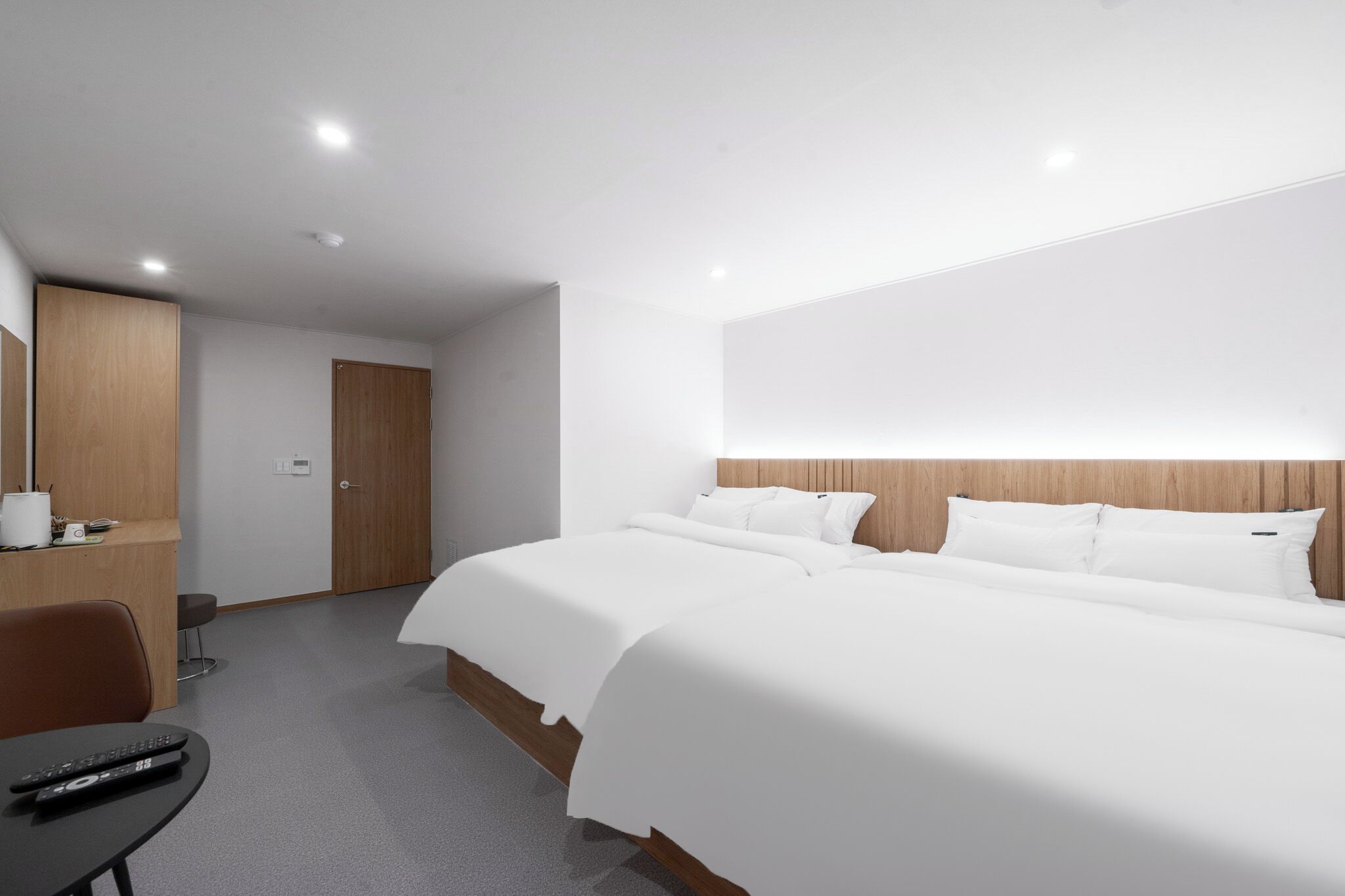 A hotel room with a large bed, a desk with a chair, a wardrobe, and a mirror.