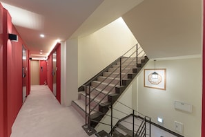 A modern interior with a staircase, red walls, and a light fixture. - Hotel Amigo Pyeongtaek Songtan (Pyeongtaek)