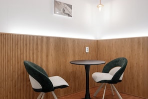A corner room with wooden panel walls, a round table, and two chairs. - Hotel Amigo Pyeongtaek Songtan (Pyeongtaek)