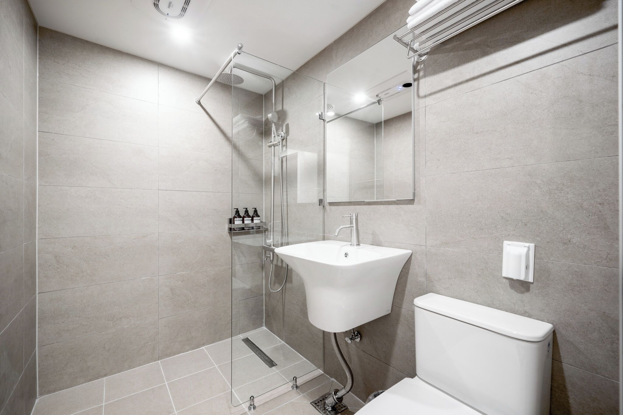 A modern bathroom with a glass shower enclosure, a white sink, and a toilet.
