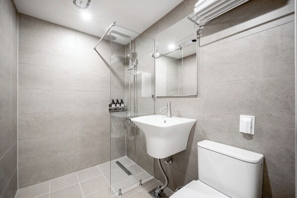 A modern bathroom with a glass shower enclosure, a white sink, and a toilet. - Hotel Amigo Pyeongtaek Songtan (Pyeongtaek)